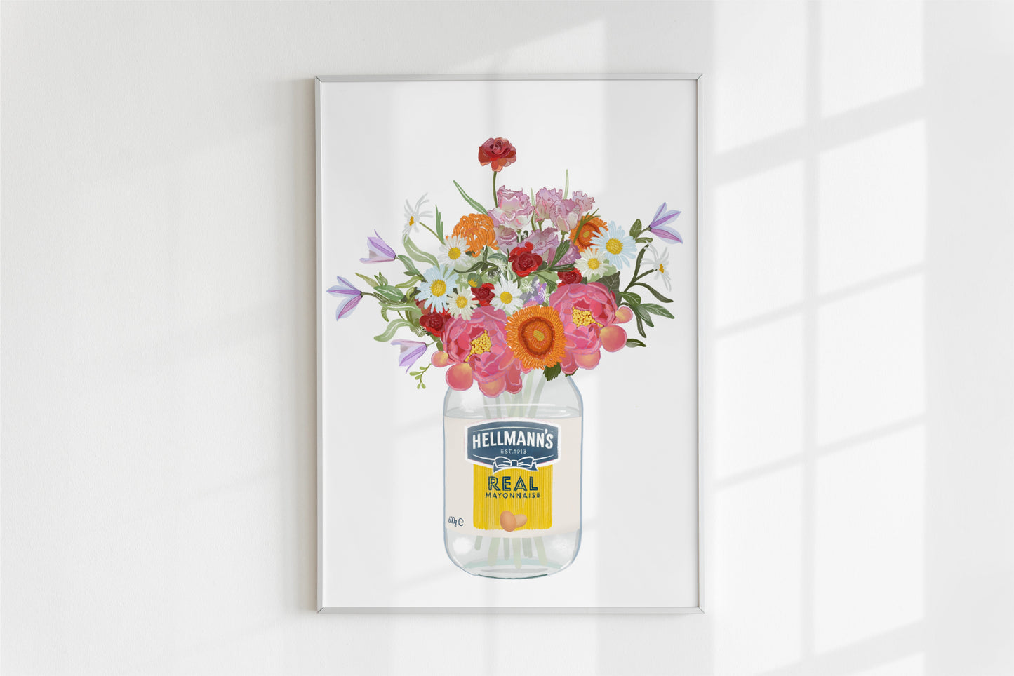 Framed artwork of flowers in a Hellmann's mayonnaise jar on a white wall.