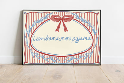 landscape orientation print with a beige background, pink stripes and a pink bow with red outline in the top middle. blue outlines of leave form an oval in the center and the quote reads in blue hand writing "less drama more pyjama"
