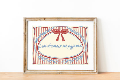 landscape orientation print with a beige background, pink stripes and a pink bow with red outline in the top middle. blue outlines of leave form an oval in the center and the quote reads in blue hand writing "less drama more pyjama"